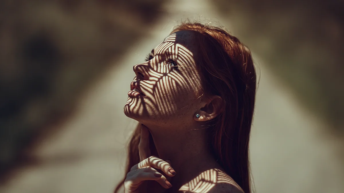 A woman with shadows dancing on her beautiful skin